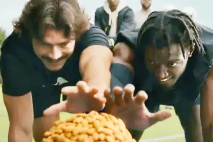 2 men reaching towards a pile of almonds in the foreground