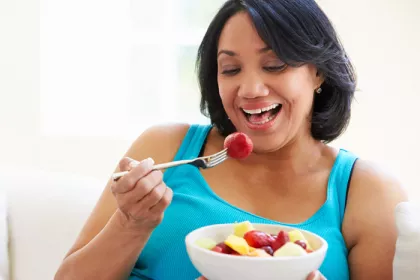 woman eating a bowl of cut fruit