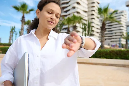 woman standing outside and looking at her watch