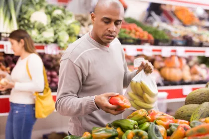 man picking out produce in a grocery store