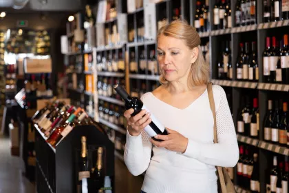 A woman checking the label on a bottle of wine