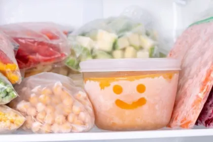 Frozen vegetables in a freezer. A bowl of frozen food with a smiley face drawn in the frost