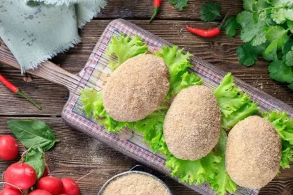 frozen Kiev cutlets lie on a wooden board covered with a thin kitchen towel. Raw frozen breaded stuffed chicken