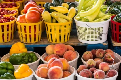Seasonal produce - baskets of tomatoes, squash, peppers, peaches and other fruit and vegetables for sale in July