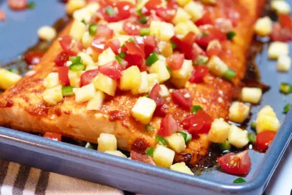 large piece of salmon covered in pineapple and tomato salsa on a pan