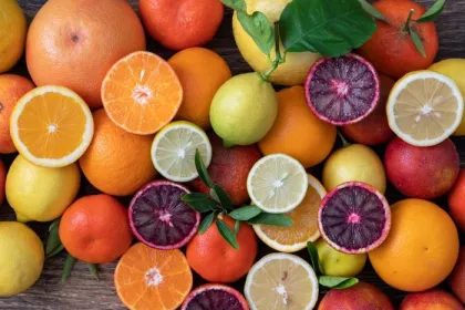 Assorted seasonal citrus fruit, including oranges, tangerines, grapefruit, limes and lemons, on a wooden table