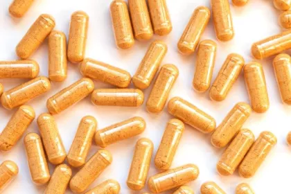 Capsules of yellow powder scattered on a white background