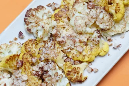 white plate of roasted cauliflower on an orange background