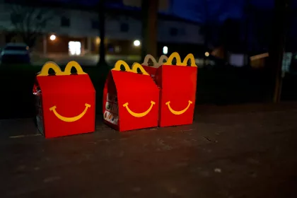 Three unopened Happy Meal boxes sitting on pavement