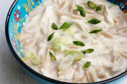 colorful blue painted bowl filled with a chicken orzo stew, garnished 
