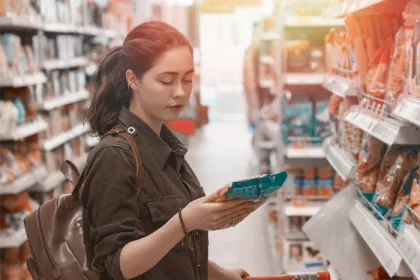 a woman reading a food package label in a grocery store