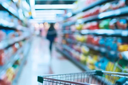 grocery cart in focus in the foreground with grocery store shelves out of focus in the background