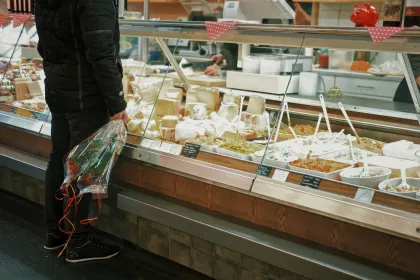 A man with flowers standing in front of a deli display containing various salads