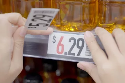 Closeup of grocery store worker increasing prices on cooking oil from $5.29 to $6.29. Rising food costs concept. 