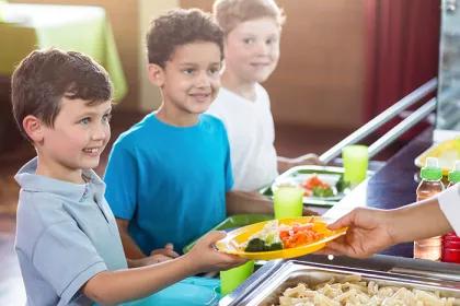 Woman serving food to schoolchildren