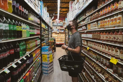 A man with a shopping basket eyeing the soda display in a supermarket