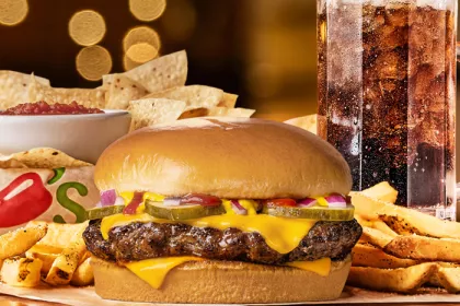 Chilis Big QP burger surrounded by fries with chips and salsa and large soda