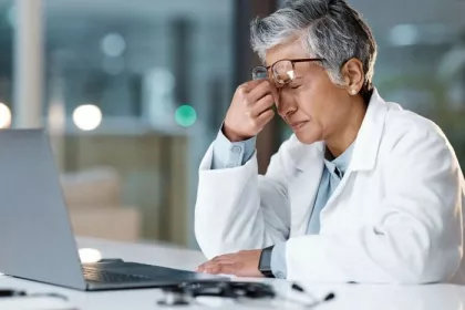 Doctor experiences headache while reviewing data on a laptop