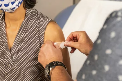 A band-aid being placed on a woman's arm after receiving a vaccine.