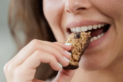 woman taking a bite of granola or protein bar