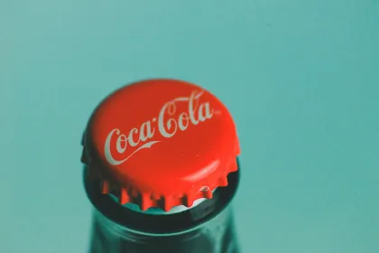 A red Coca-Cola bottle cap against a sky blue background