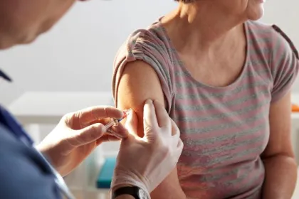 An older woman receives a vaccination shot in a doctor's office