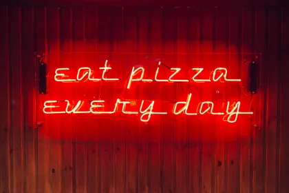 A red neon sign reading "eat pizza every day"