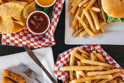 A collection of salty foods: tortilla chips, fries, a burger, and mozzarella sticks