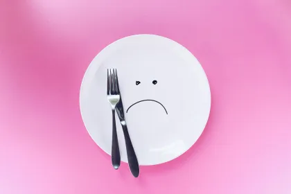An empty plate with a sad face drawn on with marker.