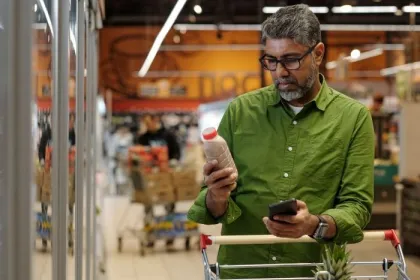 A man inagreen shirt reads the label on a packaged food product in a grocery store