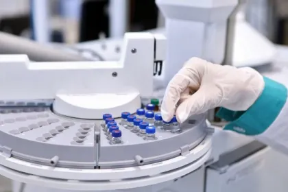 Quality control laboratory tech conducting chromatograph operation. A gloved hand makes an analysis on a gas chromatograph during the development of a new vaccine