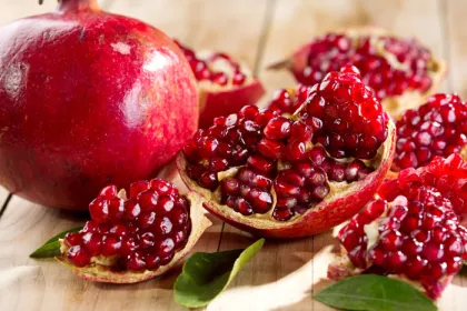 1 whole pomegranate and one split up laying next to each other 