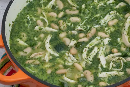 large orange ceramic pot filled with green chicken chili