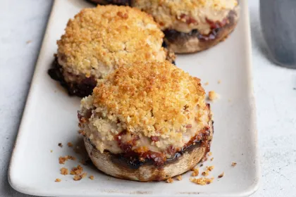 white plate with 2 stuffed Portobello mushrooms topped with breadcrumbs