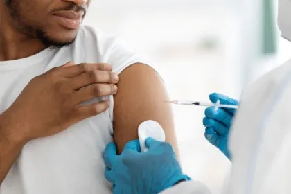 A medical professional administers a Covid vaccine to a Black man