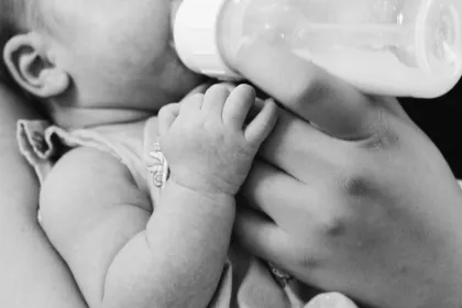 An infant drinking from a bottle in black and white