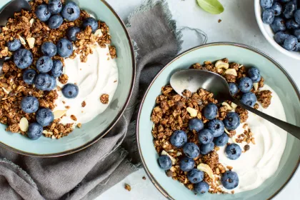 two blue bowls filled with yogurt, granola and blueberries
