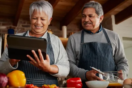couple looking at an iPad and cooking in the kitchen