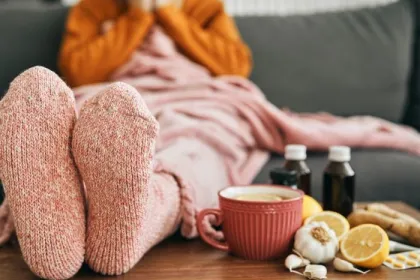 Feet wearing warm socks on a low table beside cold medicine and home remedies