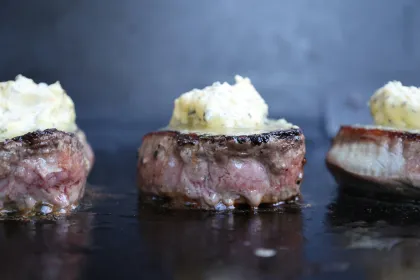 Eye fillet steaks on a grill topped with garlic butter