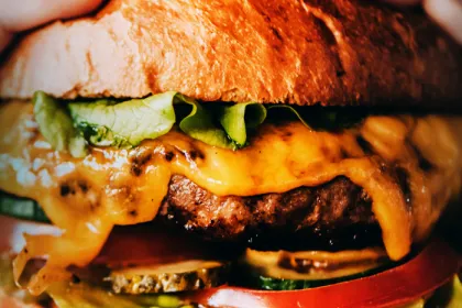 Close up of burger with cheese, pickles, tomato and lettuce.