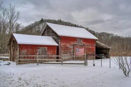 A shabby red barn with an American flag hanging on the side