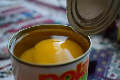 An open can of peaches in heavy syrup. 