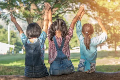 three kids sitting on a tree branch