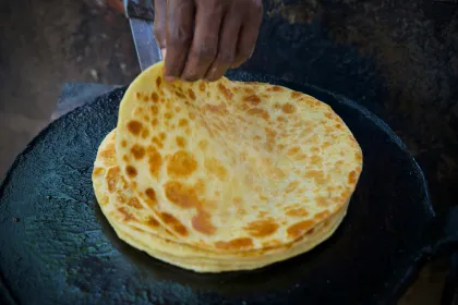 Corn tortillas being heated on a flat griddle