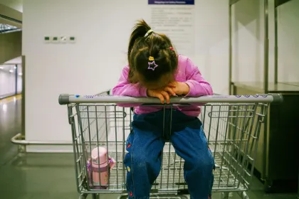 A little girl sitting in an empty shopping cart.