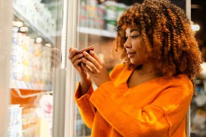 A woman reads the labels of a refrigerated product at the grocery store
