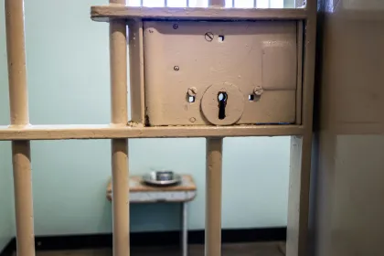A locked prison cell with a metal food container inside.