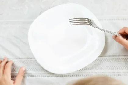 A child holds a fork over an empty plate
