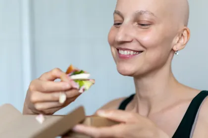 bald woman eating a salad with tofu in it